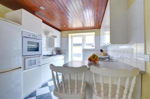 a kitchen with white cabinets and a counter with two chairs at 2 Bed in Caernarfon oc-wag359 in Caernarfon