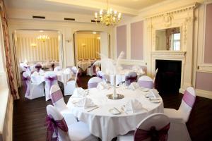 uma sala de banquetes com mesas brancas e cadeiras brancas em The Hind Hotel em Wellingborough