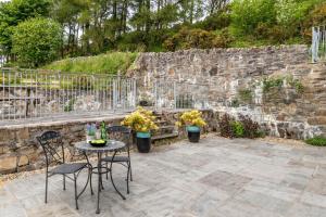 a patio with a table and chairs and a stone wall at 1 Bed in Corwen oc-fl010 in Derwen