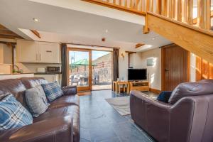 a living room with two leather couches and a kitchen at 3 Bed in Gower oc-hh407 in Llanmadoc