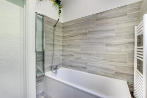 a white bath tub in a bathroom with tile walls at 4 Bed in Swansea oc-hh642 in Oystermouth +15 photos