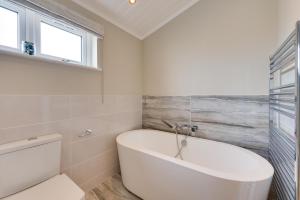 a white bath tub in a bathroom with a window at 3 Bed in Burnham Market oc-2333 in Burnham Market +2 photos