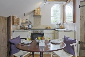 a kitchen with a table with a bowl of fruit and wine glasses at 1 Bed in Woodbridge oc-tcl in Badingham
