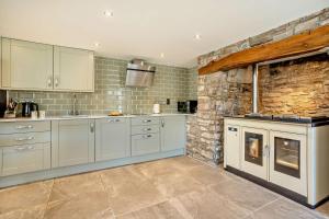 a kitchen with white cabinets and a stone wall at 3 Bed in Defynnog oc-p33133 in Devynock