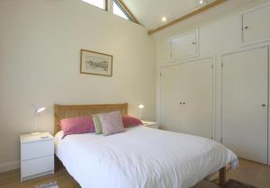 a bedroom with a bed with white sheets and pink pillows at 1 Bed in Beccles oc-mcn in Henstead