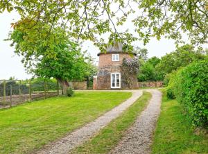 an old brick house with a tree and a dirt road at 1 Bed in Wickham Market oc-samp in Wickham Market