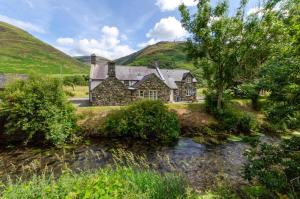 an old stone house with a river in front of it at 3 Bed in Tywyn oc-bow248 in Abergynolwyn