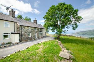 an old stone house with a tree and a windmill at 6 Bed in Barmouth oc-bow245 in Fairbourne