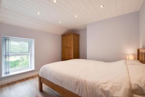 a white bedroom with a bed and a window at 2 Bed in Tregaron oc-bow289 in Tregaron