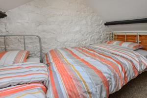 two beds in a room with a stone wall at 2 Bed in Nefyn oc-tynixs in Nefyn