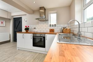 a kitchen with white cabinets and a sink at 3 Bed in Abersoch oc-16maes in Abersoch +11 photos