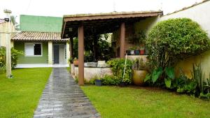 a garden with a pathway leading to a house at SUÍTE em casa FRENTE AO MAR - Acesso à PRAIA, CHURRASQUEIRA, GARAGEM e WI-FI 80mbps - Ambiente Privativo - Itanhaém-SP in Itanhaém