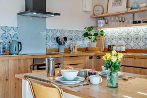 a kitchen with a wooden table with plates and flowers at 1 Bed in Builth Wells oc-p27441 in Builth Road +15 photos