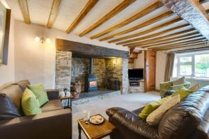 a living room with a leather couch and a stone fireplace at 3 Bed in Builth Wells oc-wal257 in Maesmynis