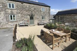 a patio with a wooden table and chairs in front of a building at 2 Bed in Brassington oc-dcgol in Brassington