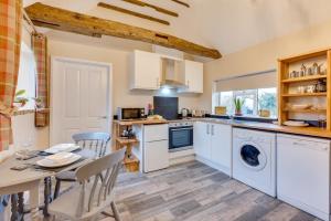 a kitchen with white cabinets and a table and chairs at 1 Bed in Great Waldingfield oc-ac1 in Waldingfield