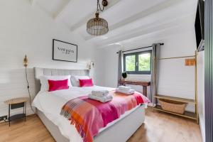 a bedroom with a large white bed with pink pillows at 2 Bed in Stradbroke oc-wopl in Stradbroke