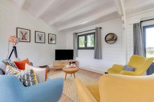 a living room with yellow and blue chairs and a television at 2 Bed in Stradbroke oc-wopl in Stradbroke