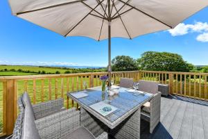 a wooden deck with a table with an umbrella at 2 Bed in Abersoch oc-atacam in Abersoch