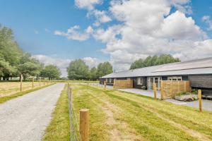 a barn with a dirt road next to a building at 10 Bed in Barsham oc-rrest in Beccles