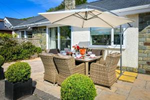 a table and chairs with an umbrella on a patio at 3 Bed in Pwllheli oc-hillvi in Llanbedrog
