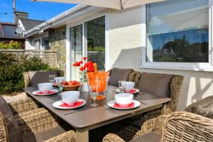 a table with cups and bowls of fruit on a patio at 3 Bed in Pwllheli oc-hillvi in Llanbedrog