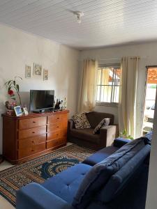 a living room with a couch and a tv at Geminado em Barra Velha SC in Barra Velha