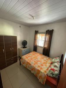 a bedroom with a bed and a dresser and a window at Geminado em Barra Velha SC in Barra Velha
