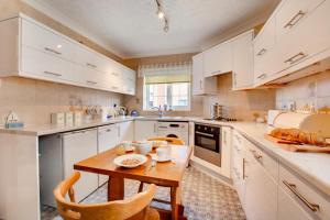 a kitchen with white cabinets and a wooden table at 2 Bed in Sheringham oc-2029 in Sheringham