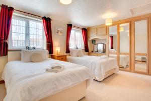 a bedroom with two beds with red curtains at 2 Bed in Sheringham oc-2029 in Sheringham