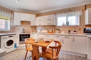 a kitchen with white cabinets and a wooden table at 2 Bed in Sheringham oc-2029 in Sheringham +5 photos