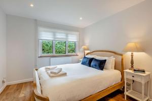 a bedroom with a bed with blue pillows and a window at 3 Bed in Acton oc-c28929 in Waldingfield