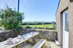 a wooden table outside a building with a stone wall at 3 Bed in Pwllheli oc-wag486 in Bryncroes