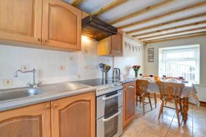 a kitchen with wooden cabinets and a table with chairs at 3 Bed in Pwllheli oc-wag486 in Bryncroes