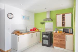 a kitchen with white cabinets and green walls at 1 Bed in Nefyn oc-n28983 in Nefyn