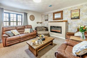 a living room with leather furniture and a fireplace at 3 Bed in Stackpole oc-c27398 in Stackpole Elidor