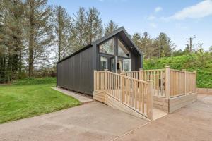 a black tiny house with a large deck at 2 Bed in Mouswald oc-b33444 in Mouswald
