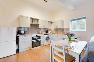 a kitchen with white cabinets and a table with chairs at 1 Bed in Chedgrave oc-2250 in Chedgrave +5 photos