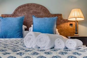 a pile of towels on a bed with blue pillows at 1 Bed in Wymondham oc-e32664 in Wymondham