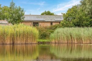 a house with solar panels on the roof next to a lake at 3 Bed in Shebbear oc-l32583 in Shebbear