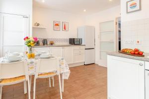 a kitchen with white cabinets and a table with chairs at 2 Bed in Tenby oc-pw1031 in Tenby