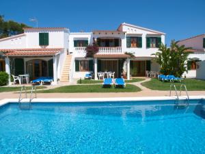 a villa with a swimming pool in front of a house at Apartamentos Arenal Playa in Punta Grossa