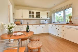 a kitchen with white cabinets and a wooden table and chairs at 3 Bed in Llanbedrog oc-gerddi in Llanbedrog +8 photos