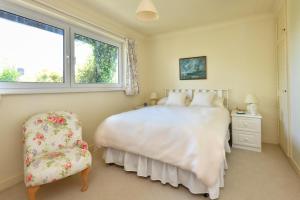 a bedroom with a bed and a chair and a window at 3 Bed in Llanbedrog oc-gerddi in Llanbedrog