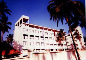 un edificio bianco con palme di fronte di Sopanam Heritage a Guruvayoor