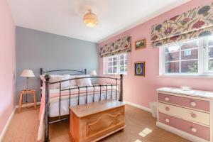 a bedroom with a bed and a dresser and two windows at 3 Bed in Ledbury oc-s32045 in Ledbury