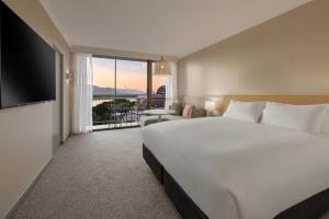 a hotel room with a large bed and a balcony at Pacific Hotel Cairns in Cairns