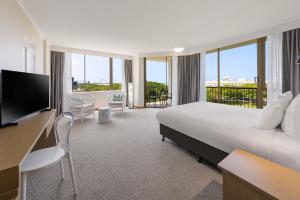a hotel room with a large bed and a balcony at Pacific Hotel Cairns in Cairns +41 photos