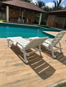 two lounge chairs sitting next to a swimming pool at Flor Da Amazônia 2, Vista para o Bosque in Ananindeua