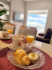 a table with a plate of food and orange juice at Piscina Lazer Frente ao Mar in Mongaguá
